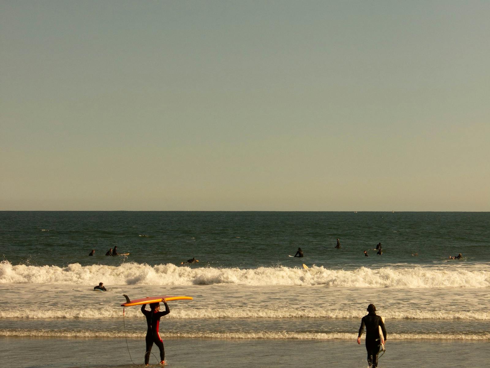 Surfers in the water at Narragansett Beach near sunset