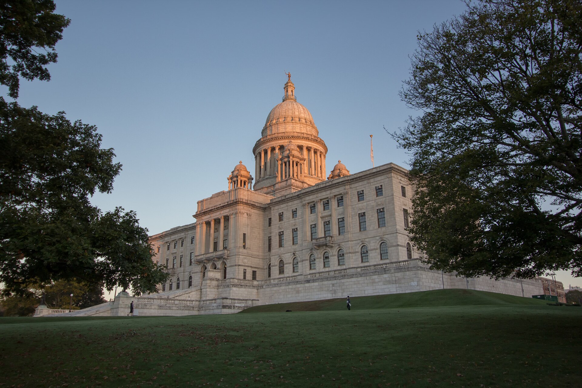 The white marble Rhode Island State House and its dome above the Providence lawn at dusk
